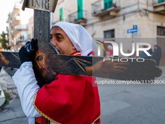 A brother is embracing the cross during the procession of the Eight Saints in Ruvo di Puglia, Italy, on Holy Thursday, March 28, 2024. The p...
