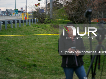 The collapsed Francis Scott Key Bridge is seen beyond a reporter at a media staging area at the Maryland Tansportation Authority headquarter...