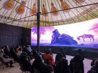Iranian families are wearing headsets to listen to a simulation of Imam Hussein's voice and the Battle of Karbala at a tent that simulates I...