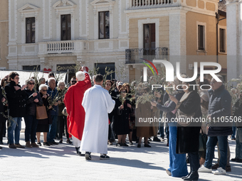 Priests celebrating blessing of olive branches and people attending ceremony are seen in Piazza Duomo square in L’Aquila, Italy, on March 24...