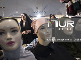 Two veiled Iranian women are looking at mannequins adorned with mandatory headscarves while shopping at the Hijab and Chastity fair in the I...