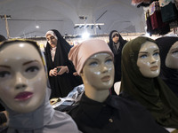 Two veiled Iranian women are looking at mannequins adorned with mandatory headscarves while shopping at the Hijab and Chastity fair in the I...