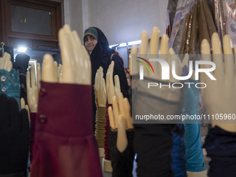 A veiled Iranian woman is looking at mannequins with hand covers while visiting the Hijab and Chastity fair at the Imam Khomeini Grand Mosqu...