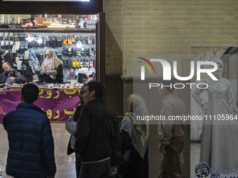Iranian visitors are standing next to a banner featuring a portrait of a female Iranian-Islamic fashion model during the Hijab and Chastity...