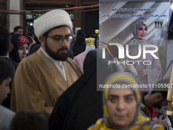 An Iranian cleric is standing next to a poster featuring a portrait of a female Iranian-Islamic fashion model during the Hijab and Chastity...
