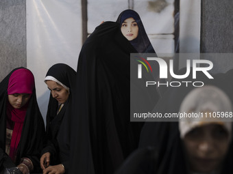 Veiled Iranian women are standing under a portrait of a female Iranian-Islamic fashion model during the Hijab and Chastity fair at the Imam...