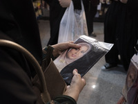 A veiled Iranian woman is looking at a portrait of a female Iranian-Islamic fashion model while shopping at the Hijab and Chastity fair in t...