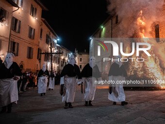 People wearing black and white hooded costumes are seen next to a giant fire during Good Friday procession in Gubbio, Italy, on March 29th,...