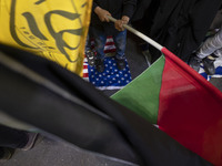 A young Iranian schoolboy is standing on the U.S. flag and waving a Palestinian flag during a protest gathering to condemn the Israeli airst...