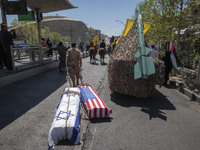 A member of the Islamic Revolutionary Guard Corps (IRGC) is carrying two coffins, symbolizing the death of Israel and the U.S., past a model...
