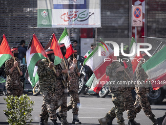 Men dressed to resemble Hamas members are carrying Iranian and Palestinian flags while participating in a rally to commemorate International...