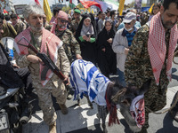 Armed military personnel from the Islamic Revolutionary Guard Corps (IRGC) are walking alongside a donkey draped with an Israeli flag and we...