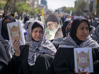 Veiled Iranian women are carrying copies of the Holy Quran and a portrait of Iran's Supreme Leader, Ayatollah Ali Khamenei, during a rally c...