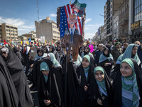 Veiled young Iranian schoolgirls are carrying an anti-U.S. placard featuring a cartoon portrait of U.S. President Joe Biden during a rally c...
