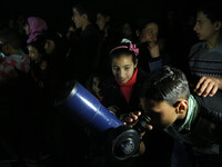 Palestinian children look through a telescope to watch the moon and stars at Al-qattan center in Gaza city on March 23, 2016. (