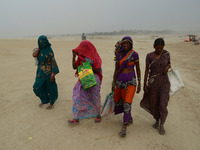 Indian women walk towards holy sangam, in a dust storm,during a hot day, in Allahabad on April 7,2016. (