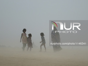 An Indian woman and kids walk towards holy sangam, in a dust storm,during a hot day, in Allahabad on April 7,2016. (