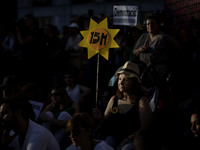 A protestor attends an assembly and displays a placard with the shape of a sun on it there's 