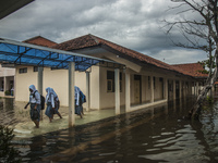 Number of student walking in flooded classroom in high school SMKN 1, Village Kramat Sari, Pekalongan, Central Java, Indonesia, on April 11,...