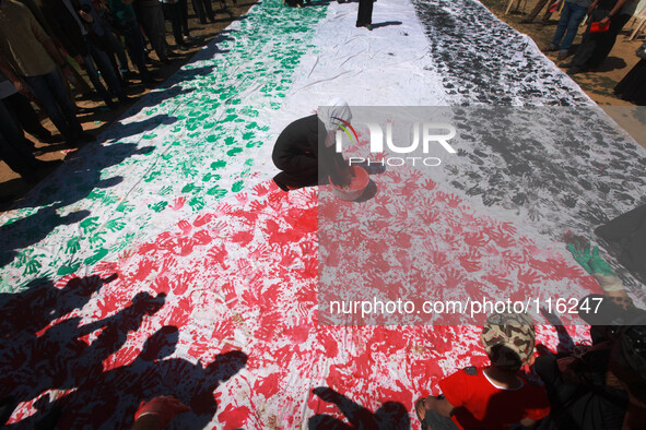 Palestinians take part in a drawing the Palestine flag by hands during a rally in Gaza city, on May 18, 2014. 