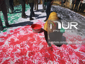 Palestinians take part in a drawing the Palestine flag by hands during a rally in Gaza city, on May 18, 2014. (