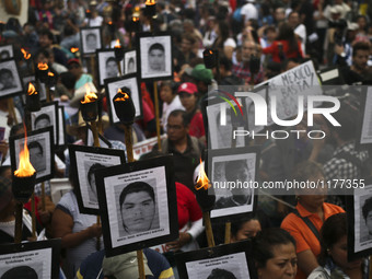 The parents of 43 missing students from Ayotzinapa teachers school hold their portraits and torches during a march 18 months after their dis...