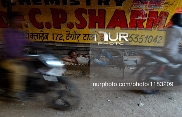 An indian man rests under a railway bridge on the side fringes of a busy road,during a hot day,in Allahabad on April 29,2016. 