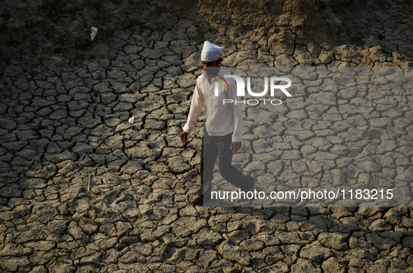 An indian farmer shows cracked surface of his farml, in shringerpur village, 17 kms from Allahabad, during a hot day on April 29,2016. 