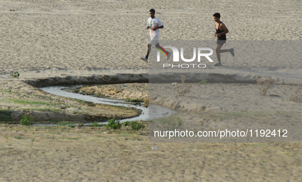 Indian sprinters run on the side of a dried and shrinked sub stream of Yamuna River , during a hot day in Allahabad on May 4,2016. 