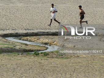 Indian sprinters run on the side of a dried and shrinked sub stream of Yamuna River , during a hot day in Allahabad on May 4,2016. (