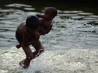 An indian kid splashes water on his younger brother to cool him off during a hot day inn Allahabad on May 23,2016. (