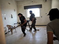 Free Syrian Army fighters carry their weapon while they run away after they opened a heavy fire on the Assad's forces in the Khan al-Assal t...