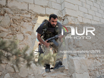Free Syrian Army fighters move through a hole in a wall in order to fight the Assad's forces in the northern town of Khan al-Assal, on 30 Ma...