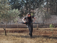 A Free Syrian Army fighter runs away of eyes of the Assad's forces as he carries his weapon in the Khan al-Assal area during clashes  for th...