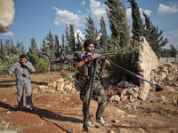 A Free Syrian Army fighter carries his heavy weapon after he opened a fire on the Assad's forces in the Khan al-Assal town near Aleppo on Ma...