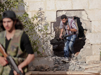 Free Syrian Army fighters move through a hole in a wall in order to fight the Assad's forces in the northern town of Khan al-Assal, on 30 Ma...