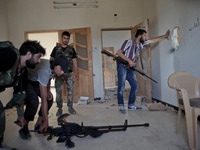 Free Syrian Army fighters sneak into a room and watch Assad's forces through gaps in Khan al-Assal town in the western of Aleppo city where...