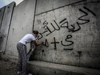 Palestinian protesters use sledgehammers to break parts from a concrete segment of a separation wall in the West Bank city of Tulkarem, on M...