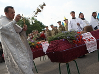 Ukrainian servicemen with Orthodox priests and other people attend a mass funeral ceremony in front of the memorial for the defenders of Kie...