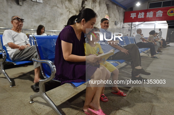 A mother reads for her child in a bomb shelter to avoid summer heat in Fuzhou, capital of southeast China's Fujian Province, July 26, 2016....