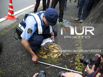 Police investigators measuring the distance of a found object from the wall, dropped by the suspect in front of the entrance of Tsukui Yamay...