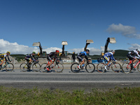 Operators of excavators cheer in the background of the breakaway of riders during the opening stage of the Arctic Race of Norway from Bodo t...