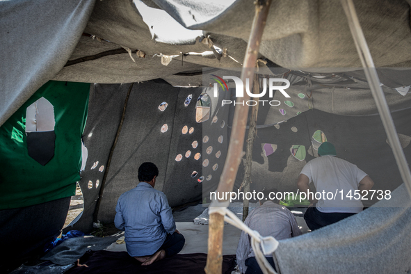 Refugees man pray at a makeshift refugee camp on the Serbian side of the border with Hungary near the town of Horgos on August 12, 2016. 