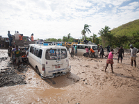 After the bridge in Ti Goave collapsed because of the hurricane, people try to walk or drive through the river to continue on the road from...