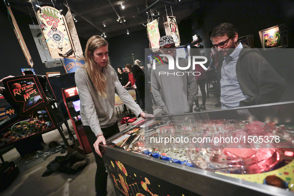 A contestant plays with a pinball machine during the Public Pinball Tournament in Vancouver, Canada, Oct. 13, 2016. People participated in t...