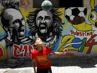 A Palestinian boy plays a ball in front of graffiti wall murals depicting football players the participants at 2014 World Cup Brazil (LtoR)...