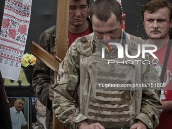 Men hold a sepulchral cross and a  portrait of dead Euromaidan activist during the burrial service (