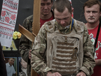 Men hold a sepulchral cross and a  portrait of dead Euromaidan activist during the burrial service (