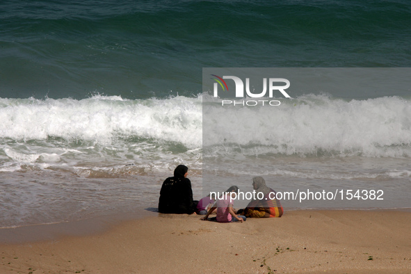 A Palestinian family sits on a Sea beach in the central Gaza Strip on June 26, 2014. Palestinian Environment Quality Authority said in a sta...