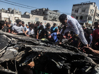 Palestinians inspect a destroyed car of two militants after Israeli airstrikes in the west of Gaza City, 27 June 2014. Two alleged militants...